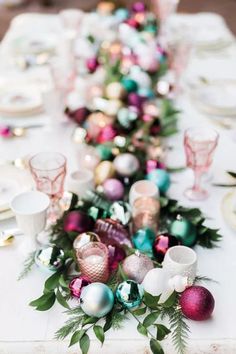 the table is set with pink and green ornaments, silverware, and white dishes