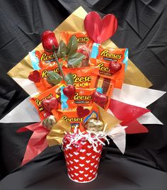 an arrangement of candy, candies and hearts in a red bucket on a black background