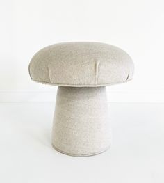 an upholstered stool sits on a white floor