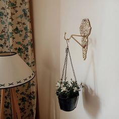 a potted plant hanging from a hook on the wall next to a flower pot