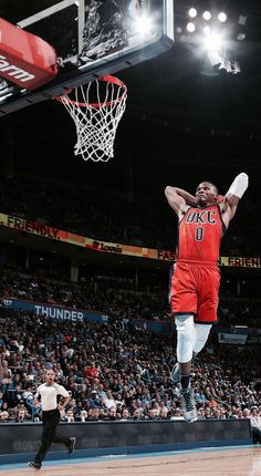 a basketball player dunking the ball in front of an arena full of people watching