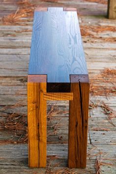 a wooden bench sitting on top of a wooden floor next to dry grass and trees