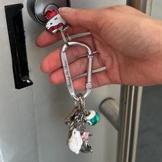 a hand holding a keychain that is attached to a door with keys in it