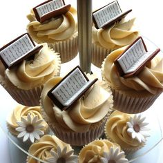 several cupcakes with white frosting and brown icing on a glass plate