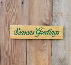 a wooden sign that says seasons greetings on the side of a wood fence with green lettering