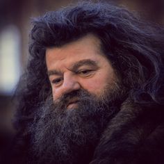 a man with long black hair and beard wearing a fur coat looking at the camera