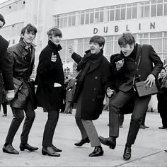 four young men are walking down the street