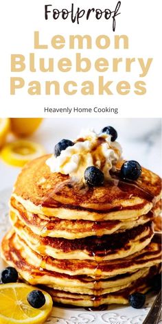 pancakes with blueberries and whipped cream are stacked on top of each other in front of lemon wedges