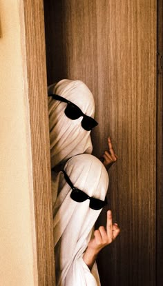 a person hiding behind a wooden door with their hands in the air and covering them from the sun