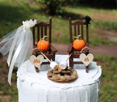 two chairs on top of a white cake with hearts and marshmallows in the middle