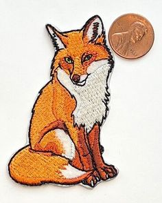 a coin sitting next to a patch with an image of a red fox on it