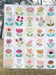 a quilt made to look like flowers is hanging on a fence