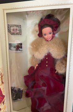 a doll in a box with a red dress and fur coat