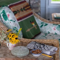 a wicker chair sitting next to a table filled with flowers and other items on top of it