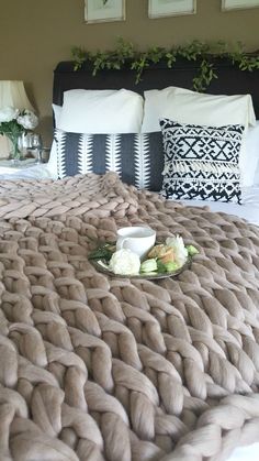 a tray with food on top of a bed next to pillows and flowers in vases