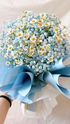 a bouquet of blue and white flowers in someone's hand