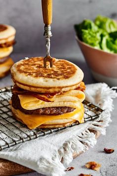 a stack of pancakes with cheese and meat being cut by a knife on a cooling rack