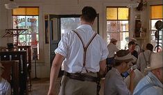 a man in suspenders is walking through a room full of people