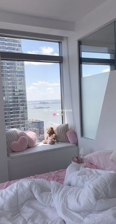 there is a teddy bear sitting on the window sill in this bedroom overlooking the city