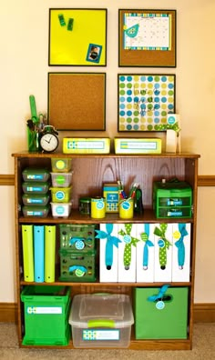 a shelf filled with lots of green and blue boxes next to pictures on the wall