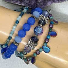 This unique bracelet set is part of my FLUTTER DREAM Collection of jewelry, created in 2023 ~  This collection features themes of flight and fantasy such as butterflies, fairies, dragonflies, & wings, and has a vivid colour story of blue, green, purple, chromatics, iridescence, silver & a touch of gold.  Any or all of the pieces in the entire collection were created to be worn together: Mix and match and have some fun!  Many lovely & unique combinations are possible. Create your own set by choosing bracelets, earrings, and a necklace. This bracelet set features primarily blue, light purple, and silver colors and includes some shell beads as well as faceted glass & silver-plated beads. All four bracelets are stretchy and comfortable to wear, easily fitting most wrists. Wear them all togethe Blue Whimsical Bracelets For Gifts, Blue Whimsical Bracelets For Gift, Whimsical Blue Bracelets For Gifts, Blue Fantasy Jewelry For Jewelry Making, Fantasy Blue Jewelry For Jewelry Making, Handmade Blue Fairycore Jewelry, Colour Story, Blue Lilac, Butterfly Fairy