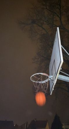 an orange basketball is in the air near a basket on top of a basketball hoop