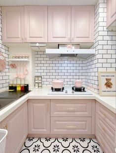 a kitchen with pink cabinets and black and white floor tiles on the walls is shown