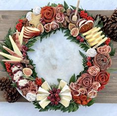 a wreath made out of fruit and flowers on a wooden board with pine cones, cinnamons and other holiday decorations