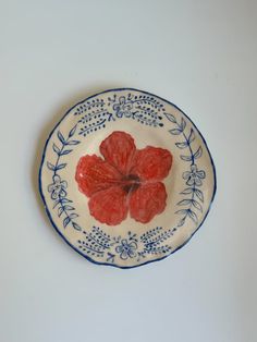 a blue and white plate with red flowers on the rim, against a white background