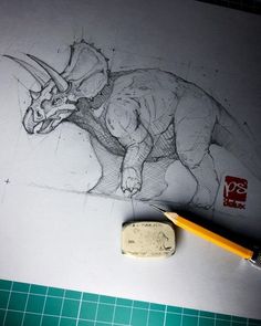 a pencil drawing of a dinosaur on paper next to a rubber stamp with a marker