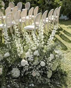 rows of chairs with white flowers and greenery on the ground in front of them