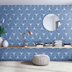 a room with blue wallpaper and a round mirror on the wall next to a table