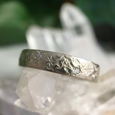 a close up of a silver ring on top of a rock with crystals in the background