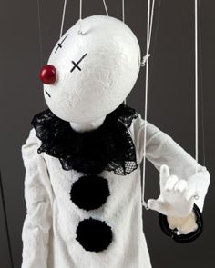 a creepy clown puppet hanging from strings with one hand in the other's pocket