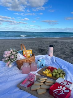 a picnic on the beach with food and drinks laid out in front of the ocean