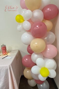 a bunch of balloons hanging from the side of a wall in front of a table