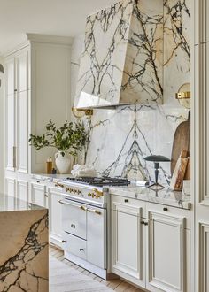 a kitchen with marble counter tops and white cabinets, along with an oven in the center