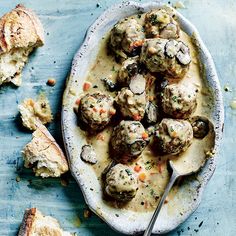 a bowl filled with meatballs covered in gravy next to some bread pieces