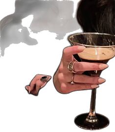 a woman's hand holding a martini glass with her fingernails and ring on it