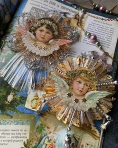 an open book with angels on it and other decorations in the pages, including brooches