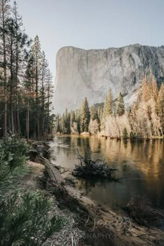 a lake surrounded by trees in front of a mountain with a large rock on the side