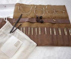 a pair of glasses sitting on top of a brown bag next to some knitting needles