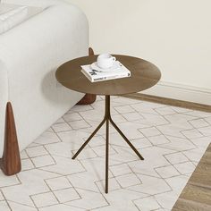 a coffee table with a book on it next to a couch and white rug in a living room