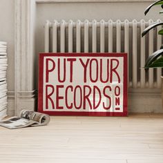 a red and white sign that says put your records on it next to a pile of books