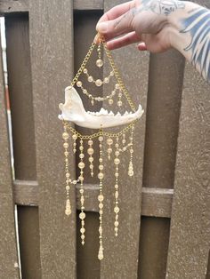 a person holding a piece of jewelry in front of a wooden fence with chains hanging from it