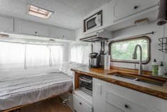 a kitchen area with a bed, sink and window