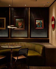 a corner booth in a restaurant with two paintings on the wall and three chairs around it