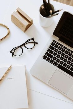 an open laptop computer sitting on top of a white desk next to a pen and glasses