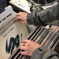 a person holding a record player in front of a stack of records with their hands