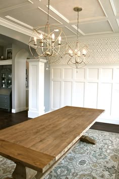 a large wooden table sitting in the middle of a room with chandelier above it